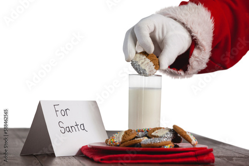 Cropped image of Santa Claus dipping cookies in glass of milk