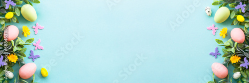 Spring or Easter background on blue. Eggs, spring leaves, flowers and colored butterflies. Long banner format.