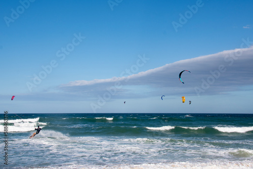 Several colorful kitesurfers sailing in a rough sea with a lot of wind