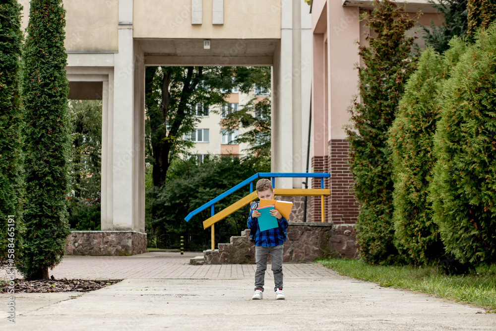 Little first grader with backpack looking the copybook, going home from school Little first grader with backpack looking the copybook, going home from school