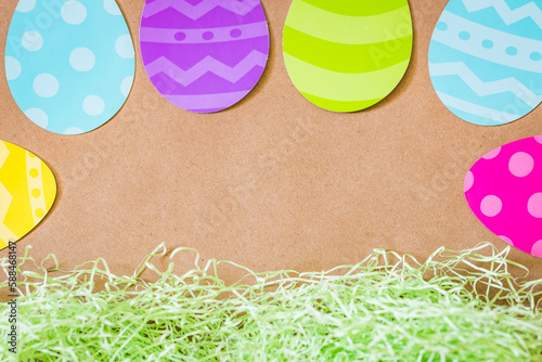 Overhead Easter background with colorful paper eggs and grass