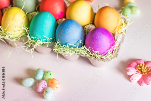 Colorful vibrant easter eggs in a basket on a light pink background