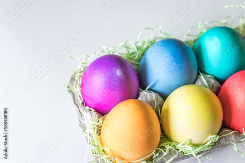 Vibrant colorful easter eggs in a basket on a white background