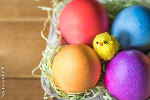 Overhead Angle of Colorful vibrant easter eggs and a yellow chick in a nest 