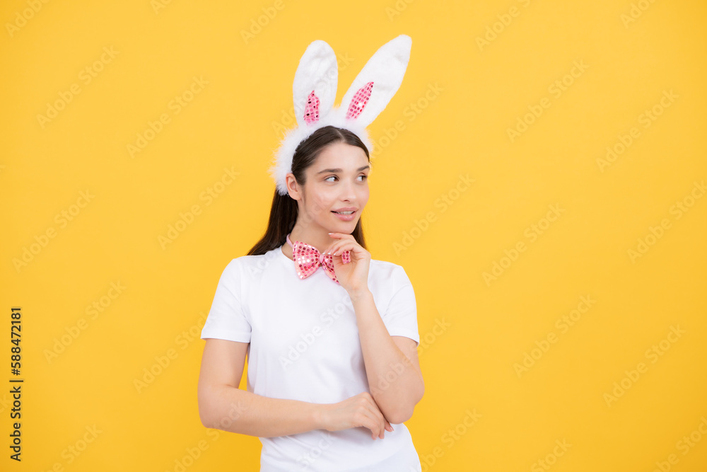 Portrait of young girl with rabbit bunny ears isolated on yellow background. Easter bunny woman looks fun.