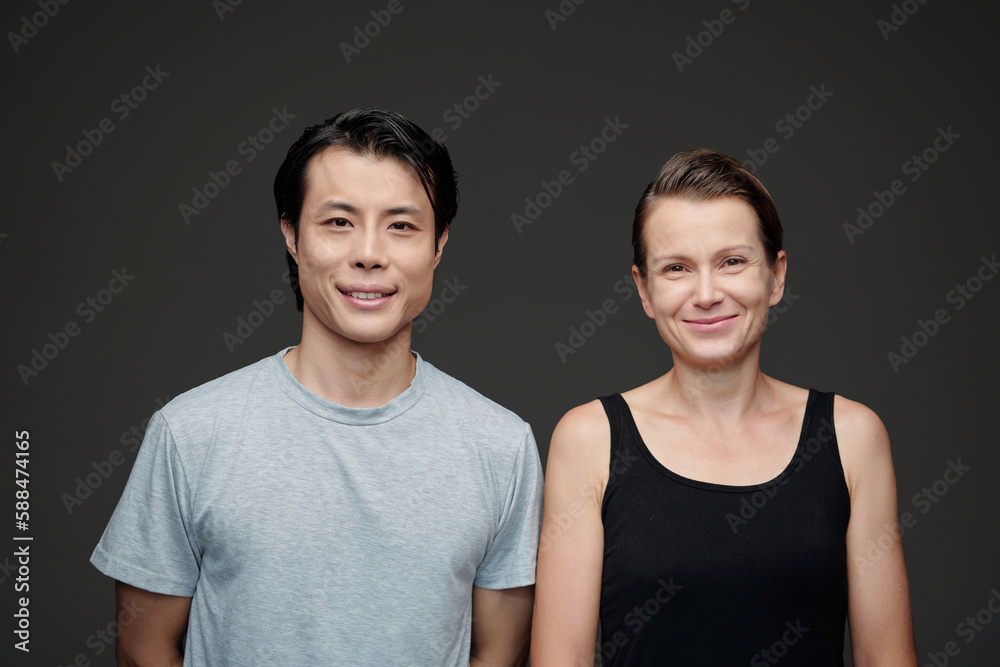 Obraz premium Portrait of smiling diverse couple standing against gray background and looking at camera