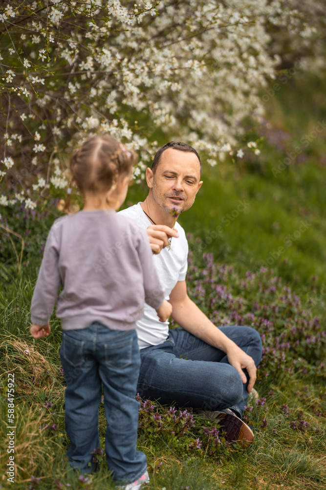 Father and daughter having a fun together under a blooming tree in spring park Petrin in Prague, Europe