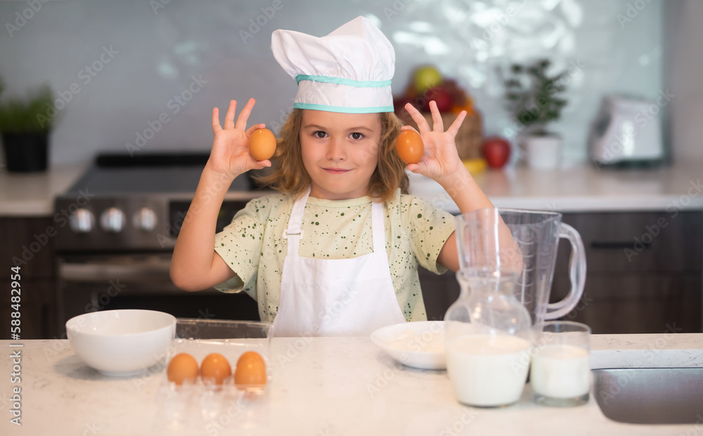Kid chef cook with eggs at kitchen. Kid chef cook is learning how to make a cake in the home kitchen. Child making tasty delicious. Eggs, milk and flour ingredients for baking cookies or pancakes. Kid chef cook with eggs at kitchen. Kid chef cook is learning how to make a cake in the home kitchen. Child making tasty delicious. Eggs, milk and flour ingredients for baking cookies or pancakes.
