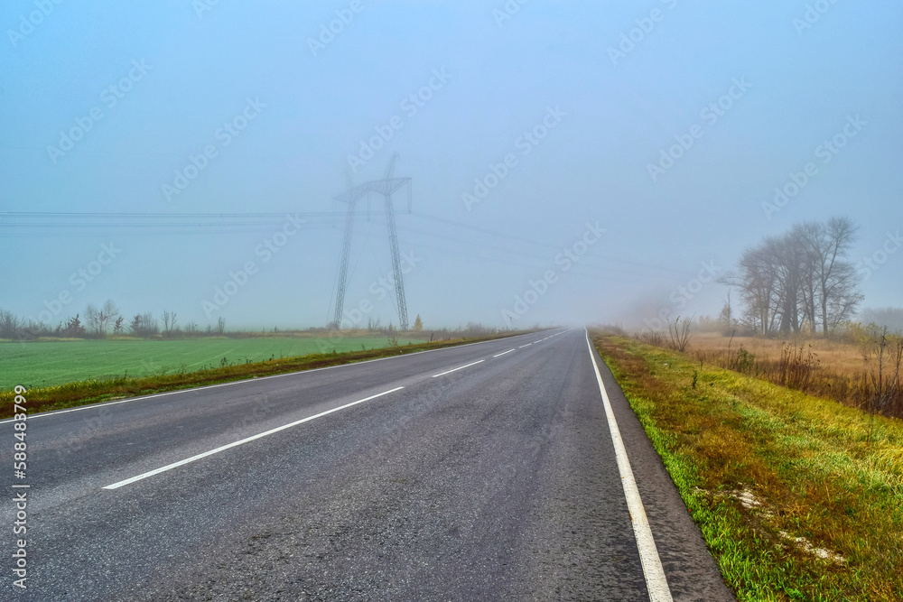 Photo of a road with a power line in the fog