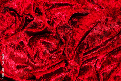 Texture of red velor corduroy fabric with folds.