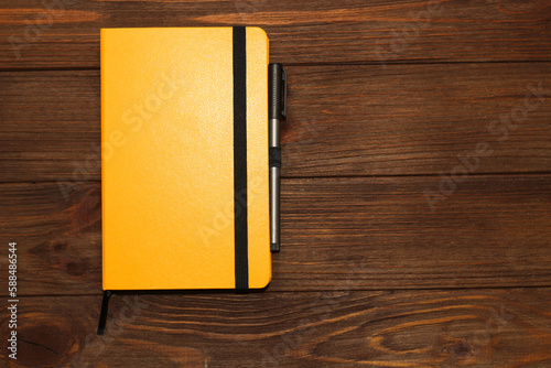 Yellow business diary on a wooden background.