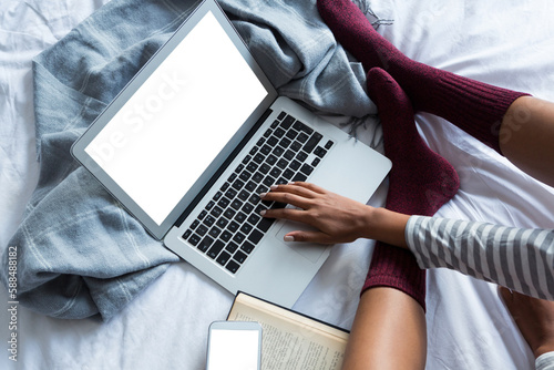 Low section of woman using laptop on bed