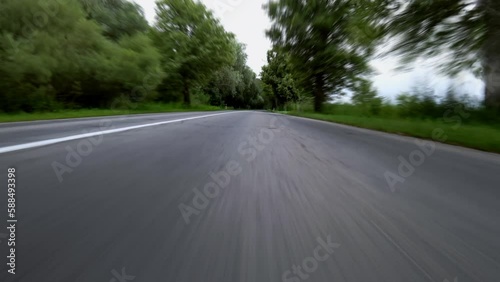 Fast driving on the highway. Low angle view on a straight asphalt road in the forest. 