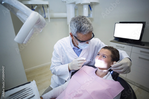 Dentist examining young patient with tools