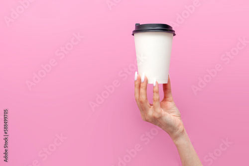 Fototapeta Naklejka Na Ścianę i Meble -  white blank paper cup of coffee in the hands of woman on pink isolated background