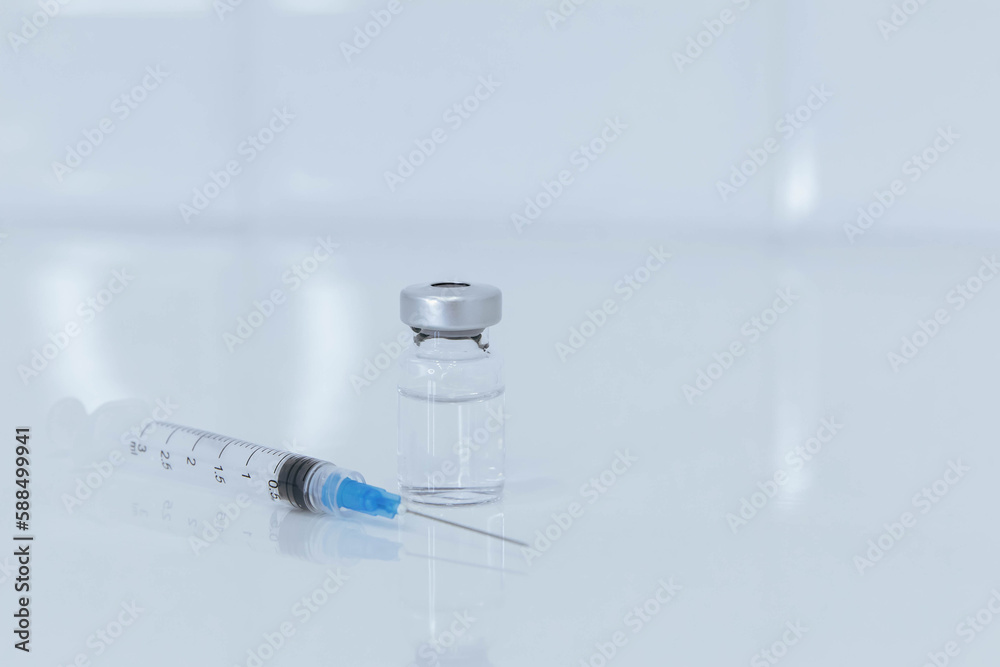 Syringe and glass bottle on white table Syringe and glass bottle on white table