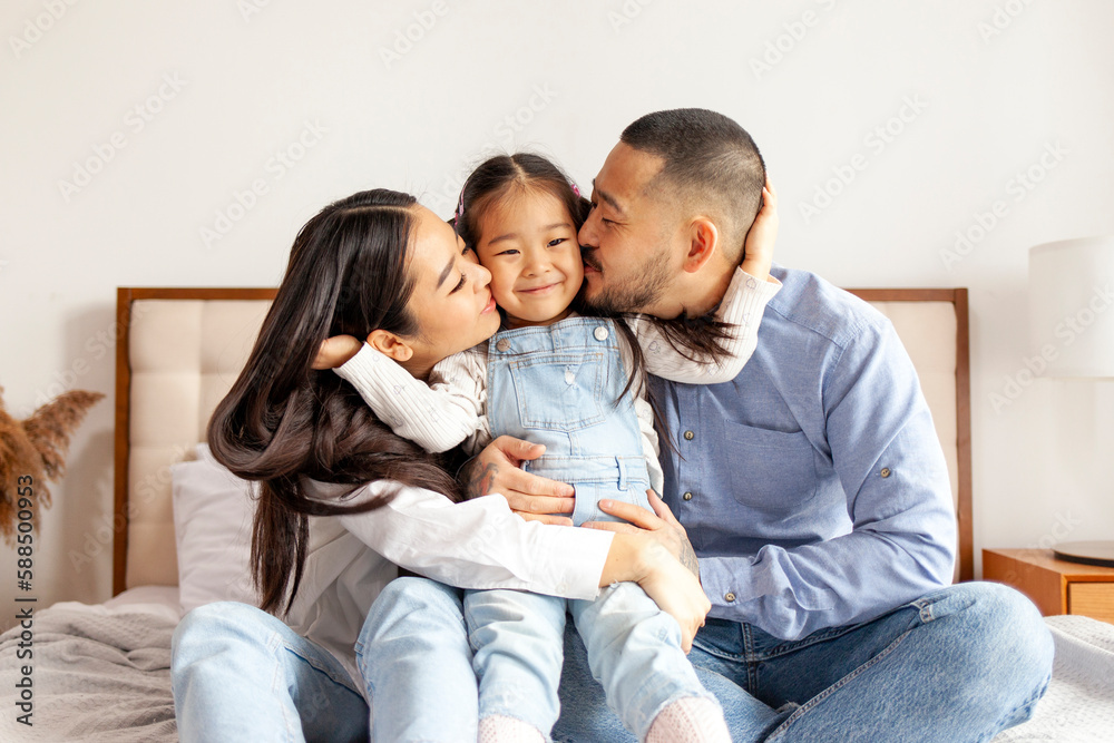 happy young asian family sit on bed together with daughter, korean little girl hug and love parents at home happy young asian family sit on bed together with daughter, korean little girl hug and love parents at home