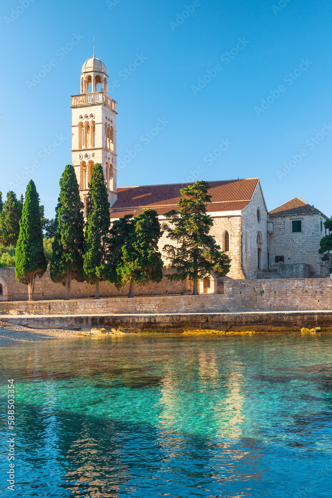 Adriatic sea bay on Hvar island with franciscian monastery in Dalmatia region, Croatia at sunrise. Vertical orientation