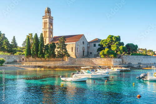 Turquoise water of Adriatic sea bay on Hvar island with franciscian monastery and boats in Dalmatia region, Croatia photo