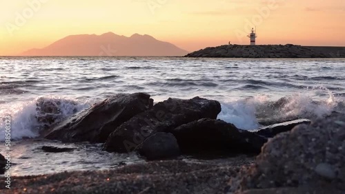 Sunset seascape with Lighthouse  view towards Samothrace Island from Kalekoy harbour Gökçeada. A man walking slowly near the lighthouse.Imbros Canakkale Turkey photo