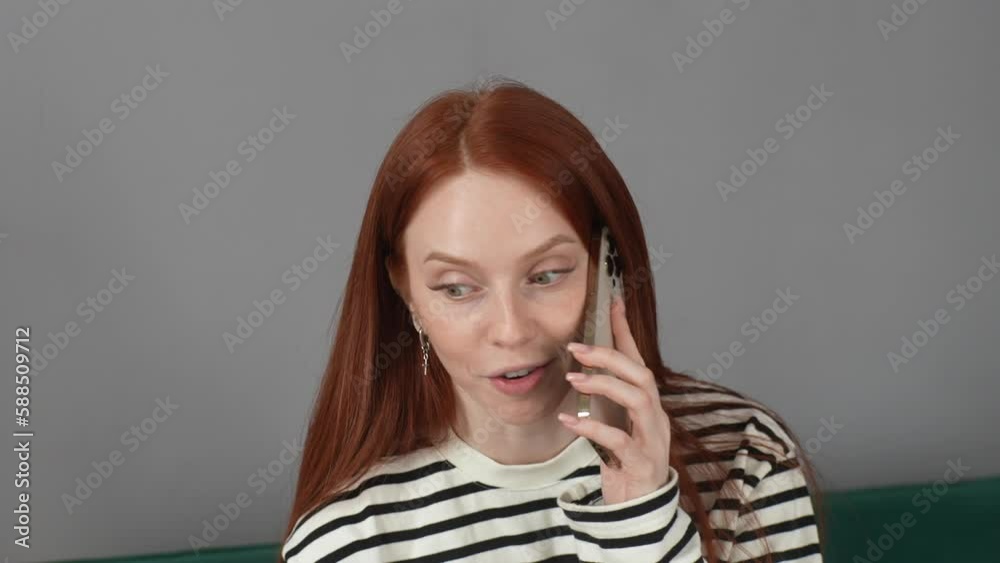 Closeup face of positive pretty young woman talking on mobile phone and smiling enjoying communication standing on gray background. Cheerful redhead female having conversation on isolated background. Closeup face of positive pretty young woman talking on mobile phone and smiling enjoying communication standing on gray background. Cheerful redhead female having conversation on isolated background.