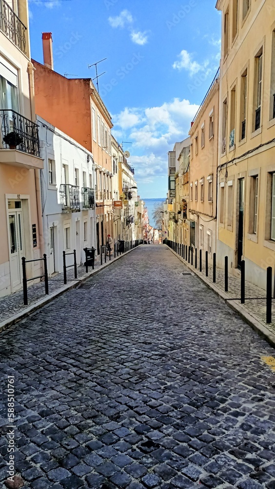 One of the streets of Lisbon that leads down to a large river and the city center