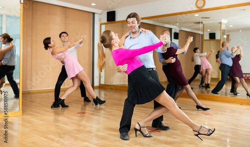 Cheerful adult woman learning to dance Vienneze waltz with partner in dancing class. Active hobby concept