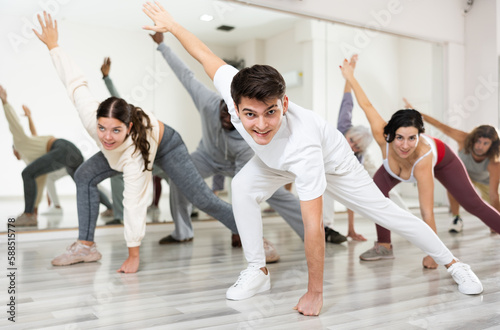 Group of active people engaged in a dance studio performing a stretching exercise during a workout