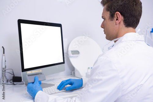 Dentist working on computer against wall