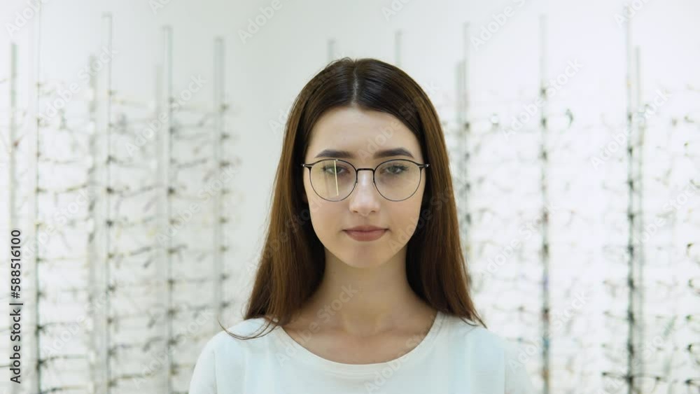 Conceived young woman choosing glasses at optics store. Health care, eyesight and vision concept