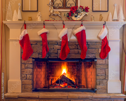 Five red stockings on the stone hearth with a blazing fire for Christmas holidays.