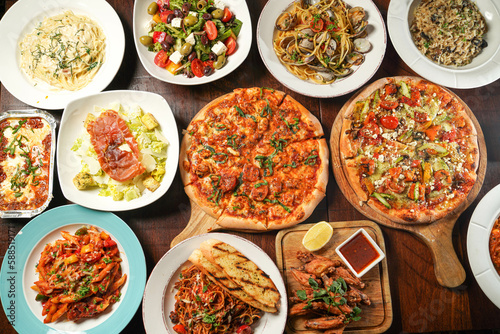 Assortment of fastfood with pizza, Lasagne, Bolognese, chicken wings, greek and caesar salad, Fettuccini, Risotto, Spaghetti served in dish isolated on wooden table top view of italian fast food