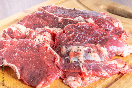 Raw sirloin steak cut into steaks on a wooden board, on a wooden table.