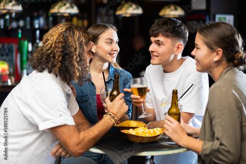 Happy friends drinking beer and chatting with each other in a restaurant