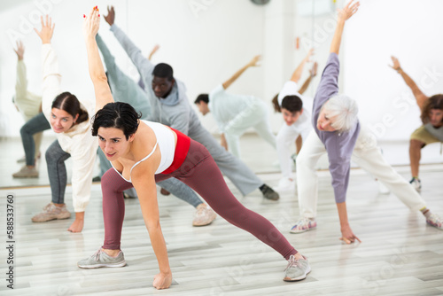 Happy young woman practising modern dance moves with other people in dance studio