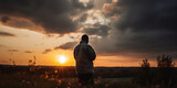Un homme de dos devant un paysage coucher de soleil et nuage