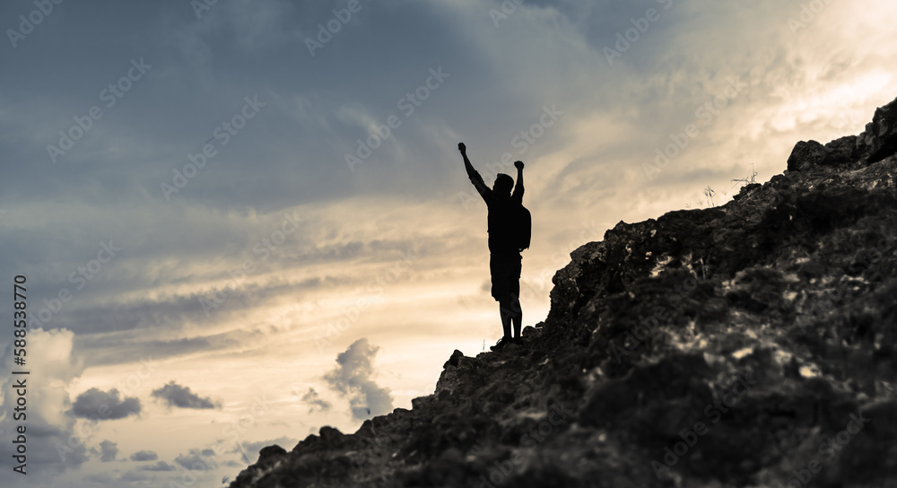 silhouette of a person on a mountain top celebrating victory 