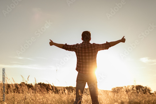 Young man feeling grateful, joyful standing outdoors in the sunrise 