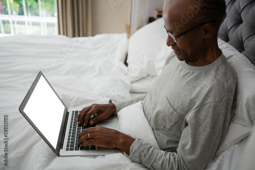 High angle view of senior man using laptop on bed