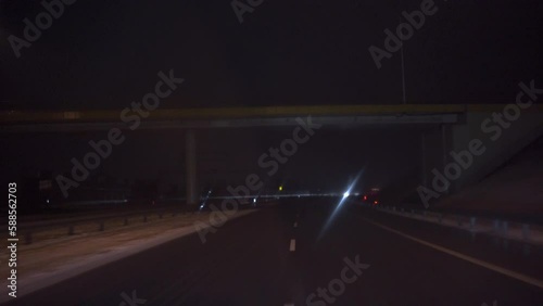 Car moving on road at night passes under bridge photo