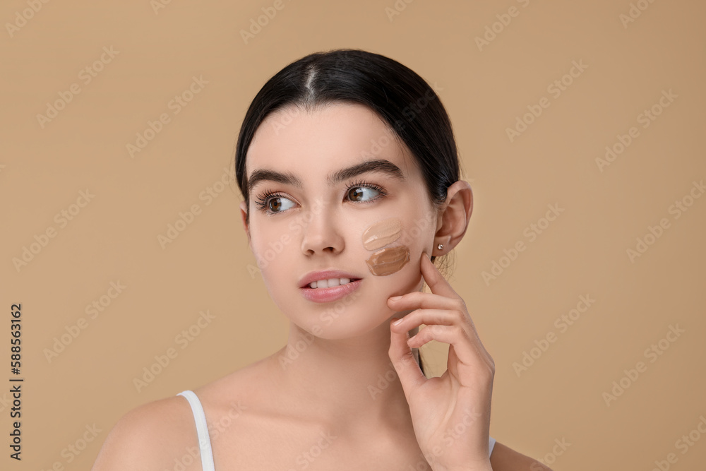 Teenage girl with swatches of foundation on face against beige background Teenage girl with swatches of foundation on face against beige background