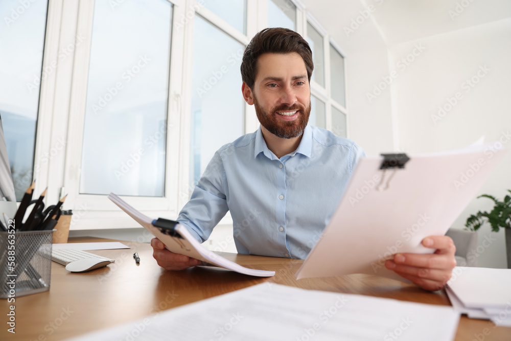 Happy businessman working with documents at wooden table in office Happy businessman working with documents at wooden table in office