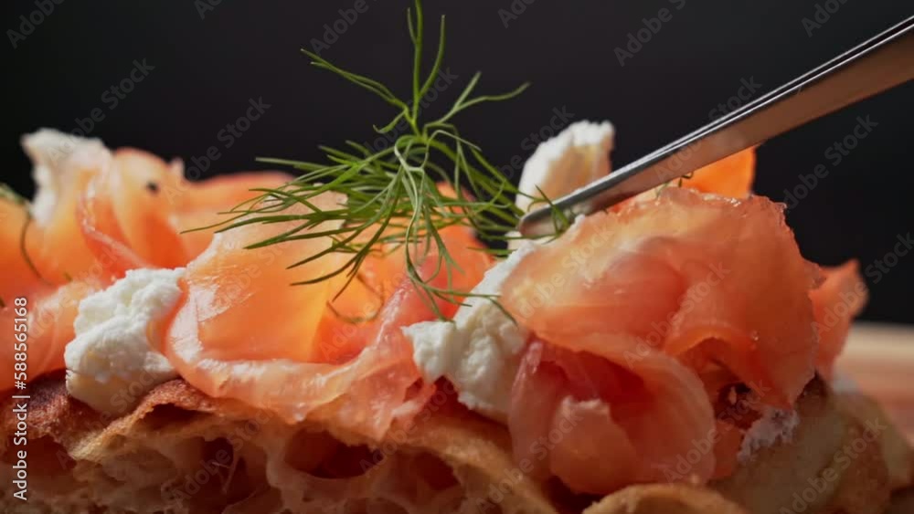 Professional gourmet chef places fresh dill on pink salmon fish with tweezers Professional gourmet chef places fresh dill on pink salmon fish with tweezers