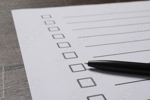 Paper sheet with checkboxes and pen on wooden table, closeup. Checklist