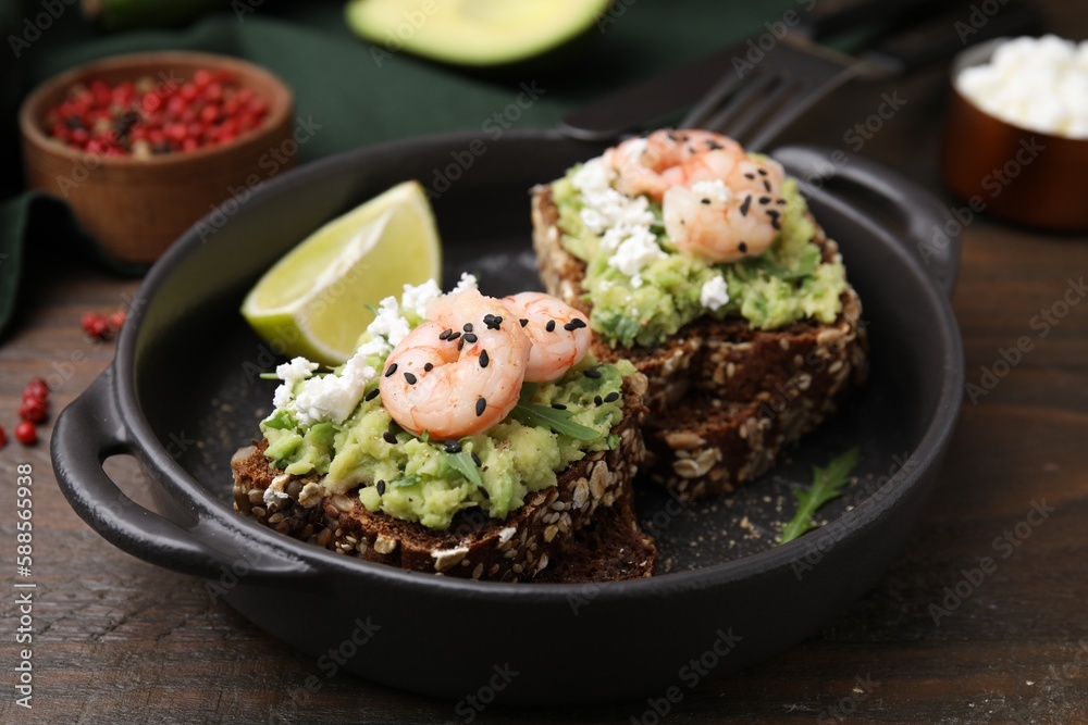 Delicious sandwiches with guacamole, shrimps and black sesame seeds on wooden table
