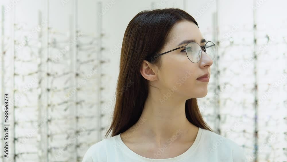 Conceived young woman choosing glasses at optics store. Health care, eyesight and vision concept Conceived young woman choosing glasses at optics store. Health care, eyesight and vision concept