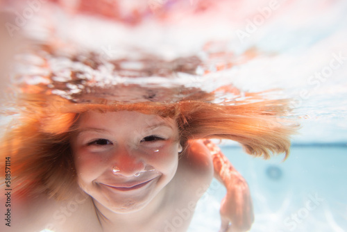Funny kids face under water. Child swim and dive underwater in the swimming pool. Summer vacation.