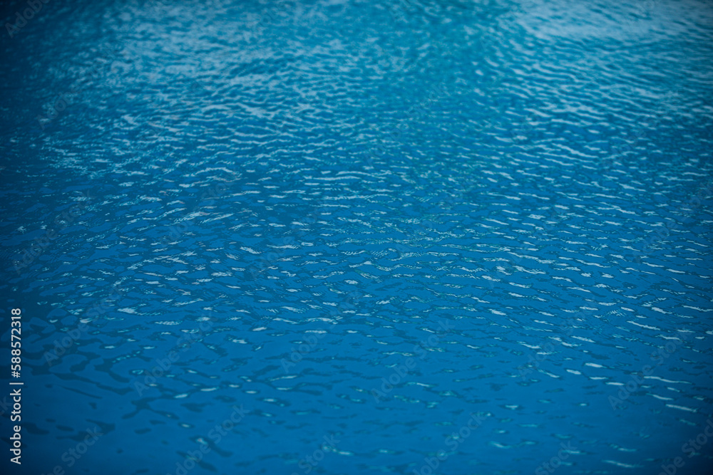 Ripple Water in swimming pool with sun reflection. Wavy water background.