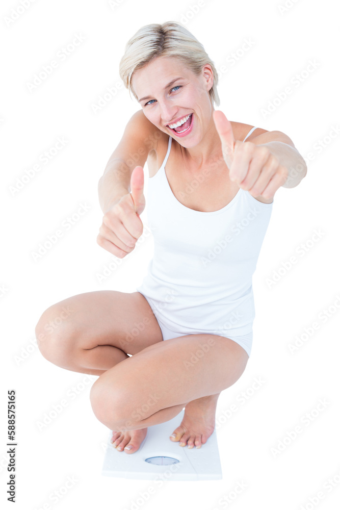 Happy blonde woman crouching on a scales with thumbs up 