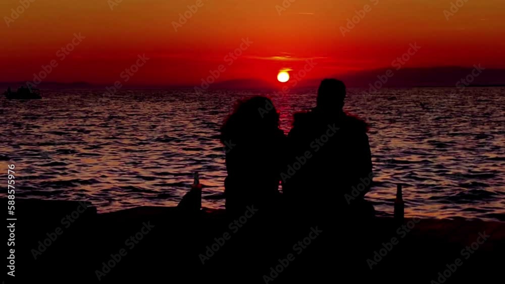 Two Loving Couples Sitting Against Sun on Beach at Twilight Sunset Footage. Two Loving Couples Sitting Against Sun on Beach at Twilight Sunset Footage.